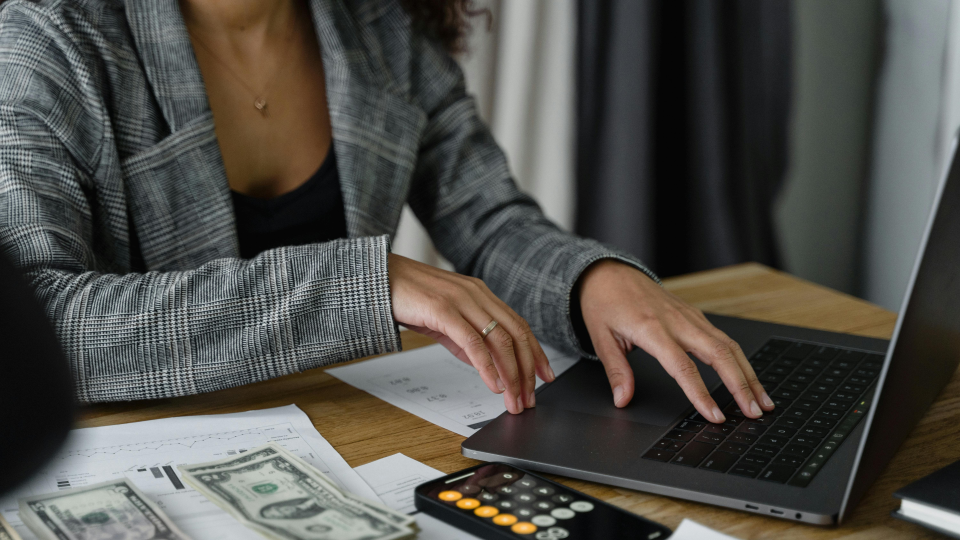 Woman typing on laptop with calculator