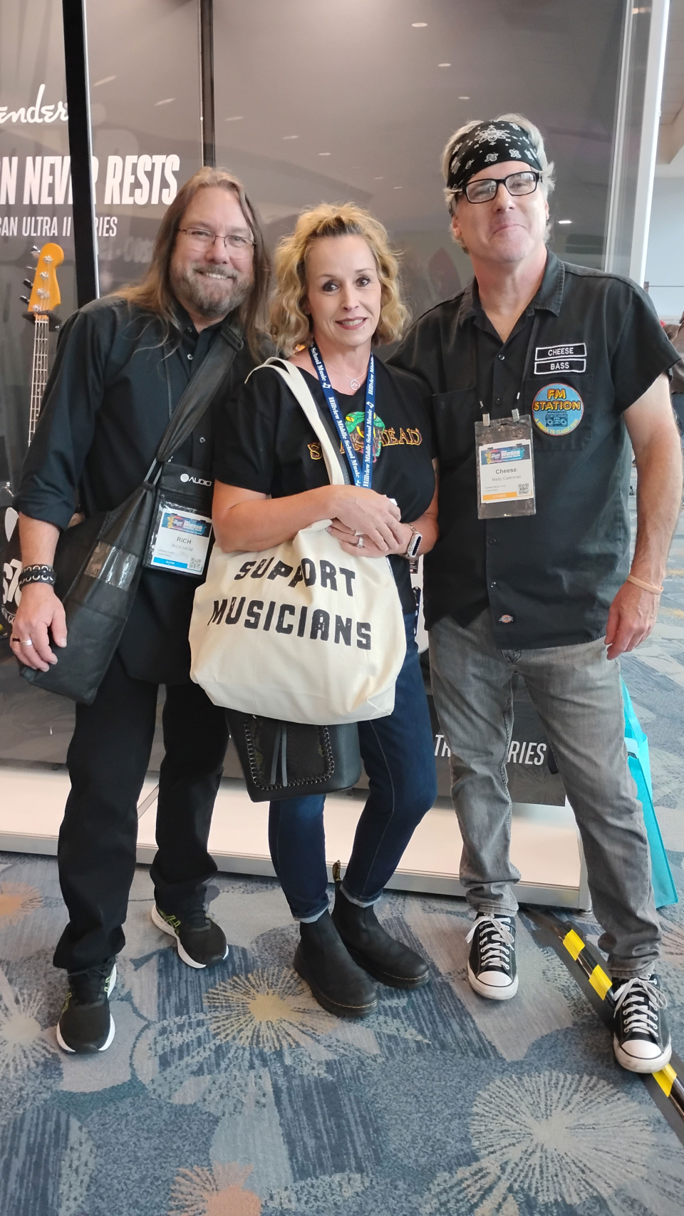 a woman with two friends holds a bag reading support musicians